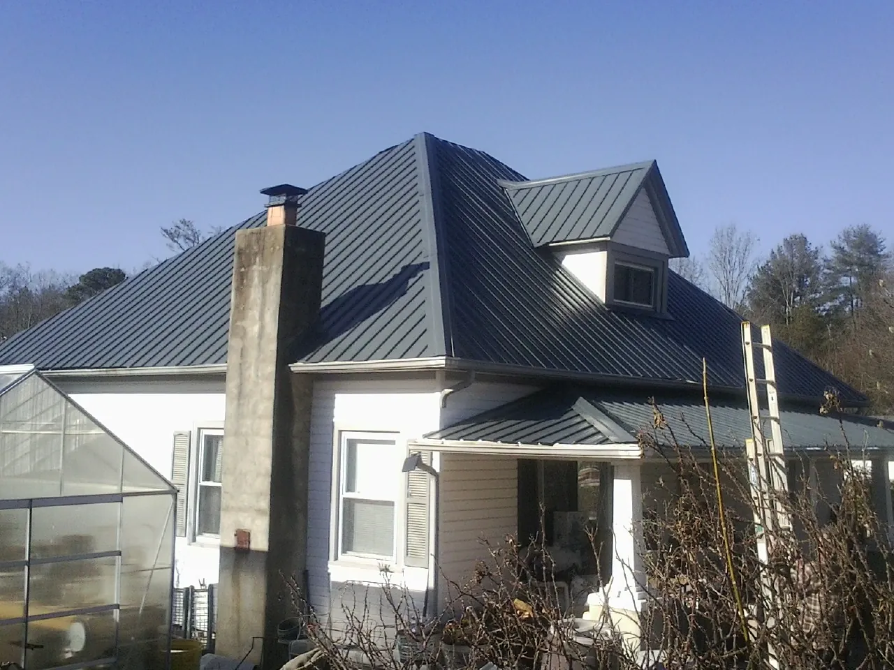 Dark blue standing seam metal roof on a white farmhouse with dormer — Slate & Tile Roof Repair by Roofing Brothers in Byram