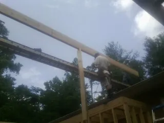 Carpenter setting a ridge beam over a new addition frame — Ice Dam Removal by Roofing Brothers in Byram