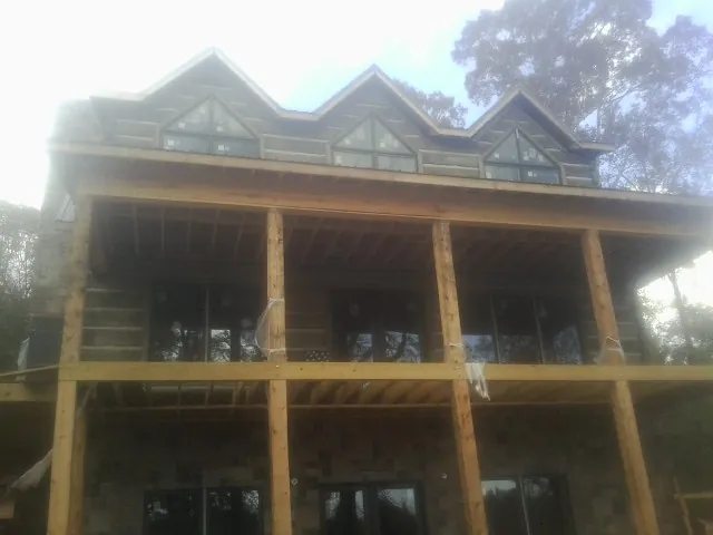 Dormers and porch framing on a large log home under construction — Roof Coating work by our crew in Byram