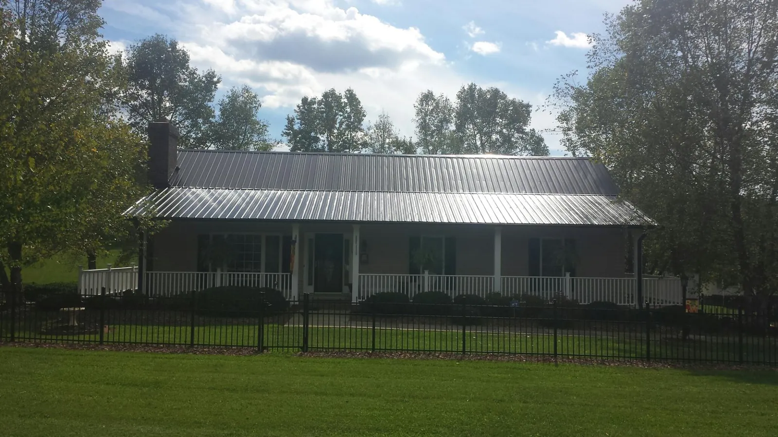 Gray metal roof on a brick ranch with a full width front porch — Gutter Guard Installation work by our crew in Byram