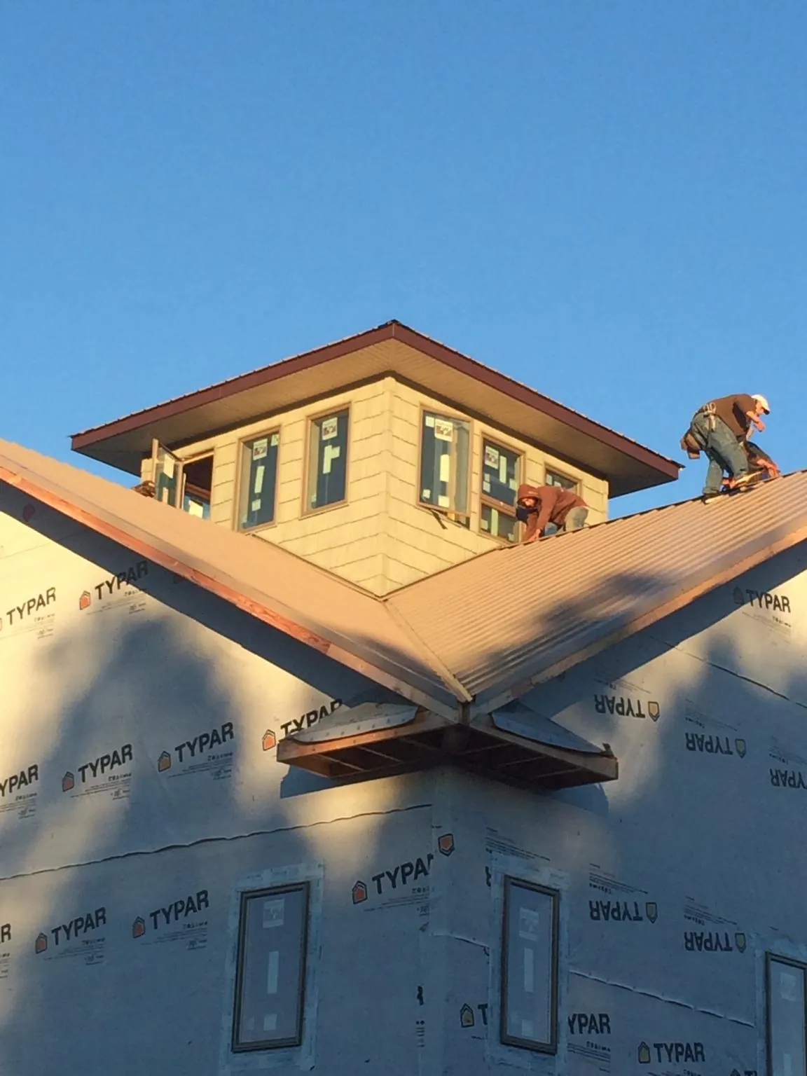 Roofers working around a rooftop cupola on a new metal roof at sunset — Roof Waterproofing in Byram by Roofing Brothers